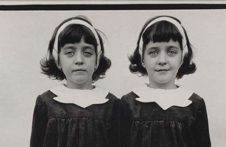 Visages de deux jumelles identiques en serre-tête et col blanc, détail d’une photographie de Diane Arbus (Roselle, 1967)