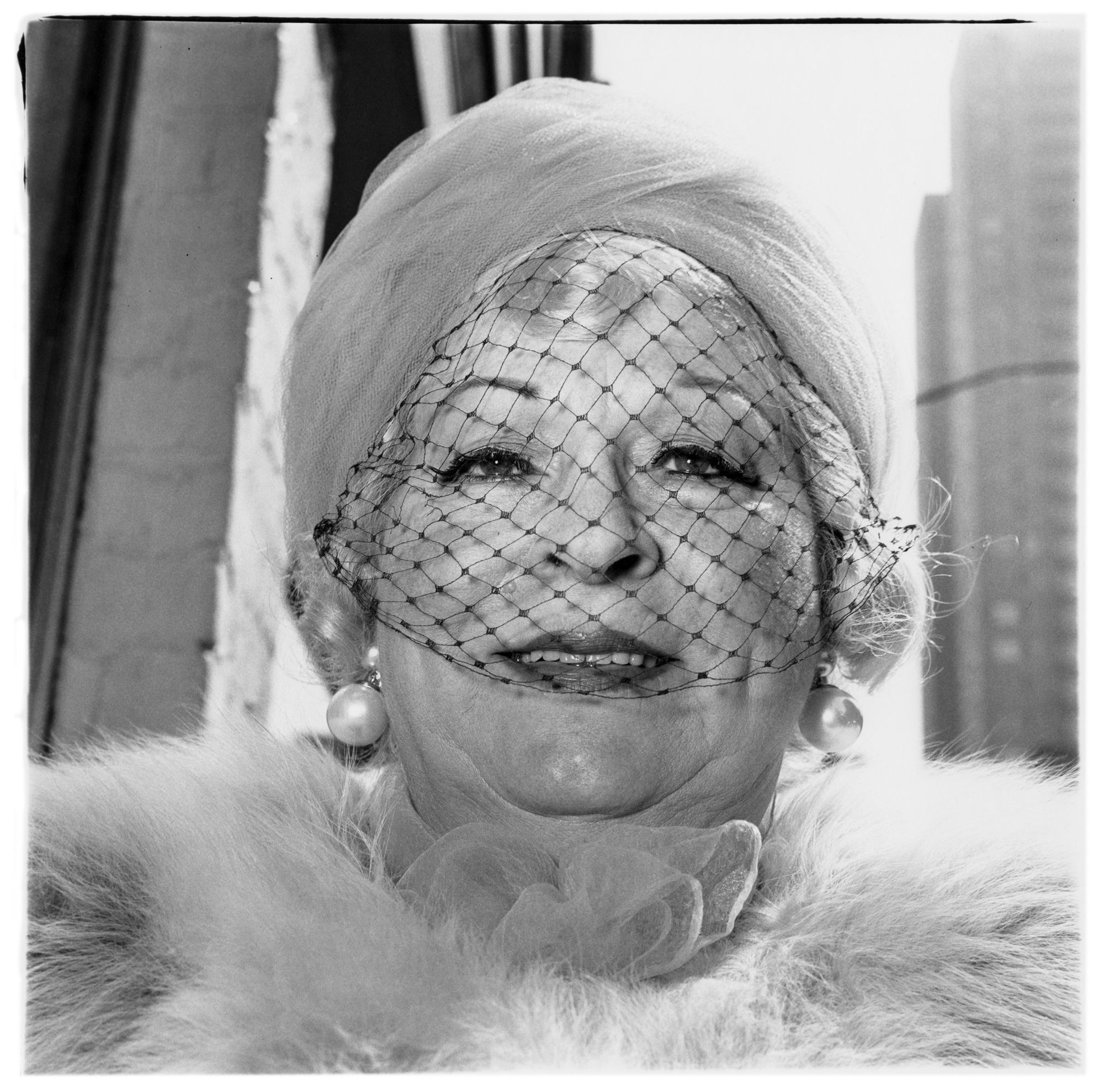 Femme âgée souriante portant une voilette, des perles et un col de fourrure sur la Cinquième Avenue, photographie de Diane Arbus (1968)