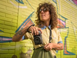 Nikon Z5IIC : le plein format à la portée des débutants Photographe tenant un Nikon Z5IIC argenté devant un mur couvert de graffitis