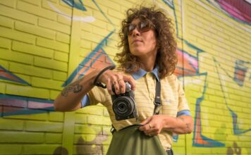 Photographe tenant un Nikon Z5IIC argenté devant un mur couvert de graffitis
