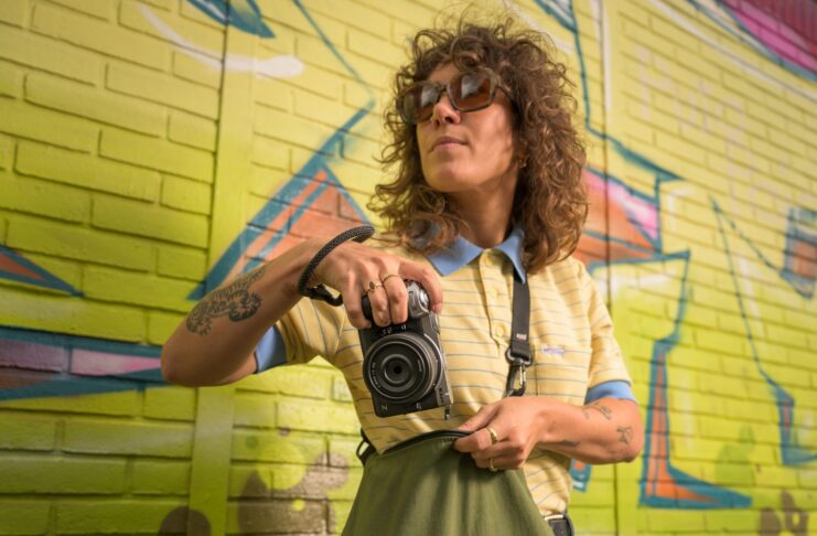 Photographe tenant un Nikon Z5IIC argenté devant un mur couvert de graffitis