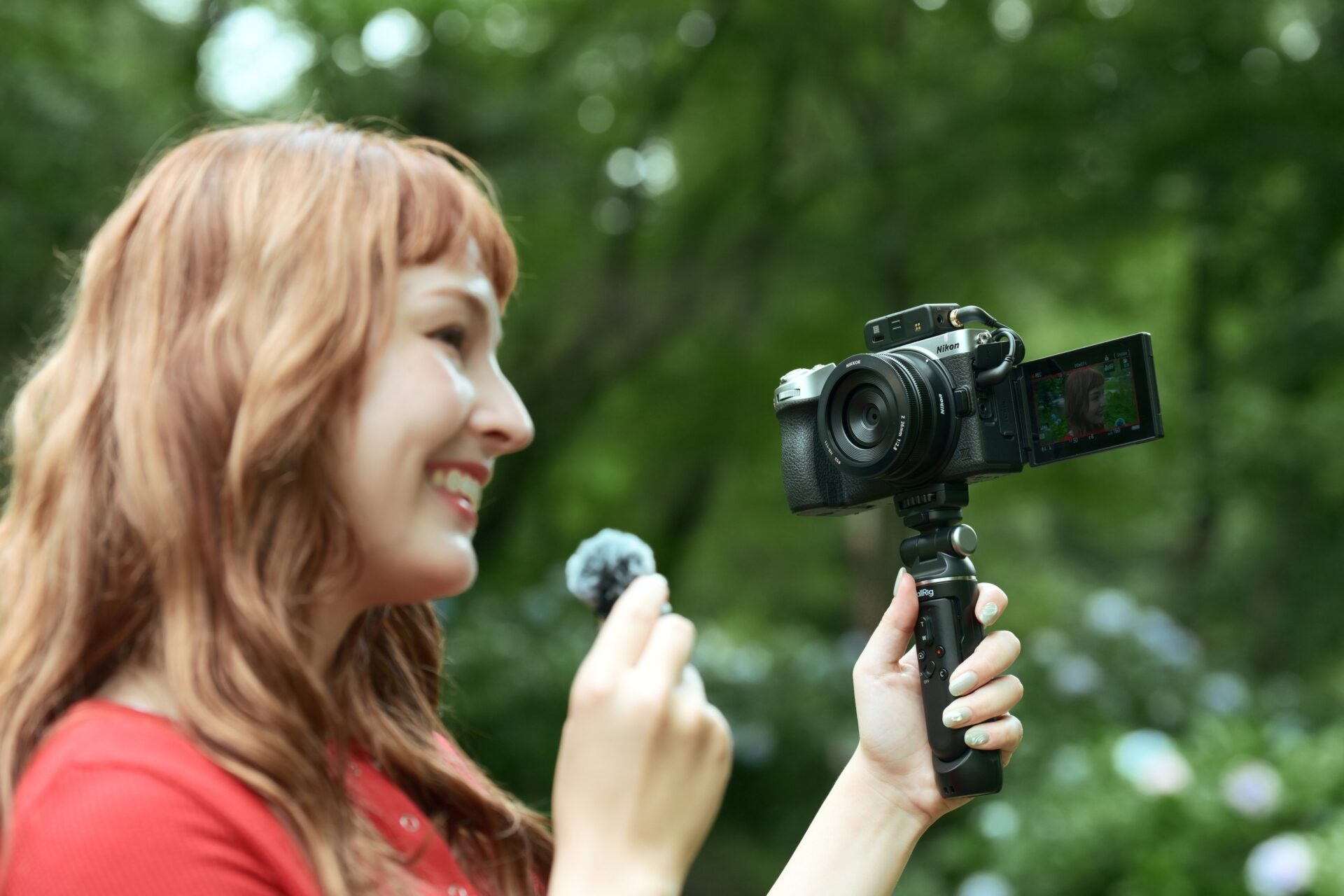 Vidéaste filmant face caméra avec un Nikon Z5IIC monté sur une poignée, écran retourné